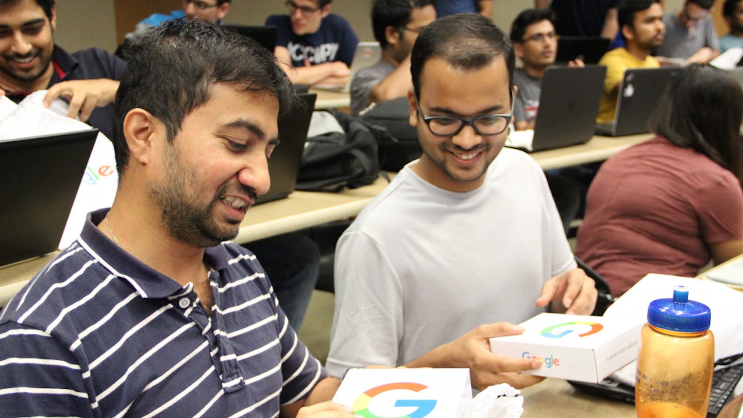 (From left to right) Master's computer science students, 35-year-old Pradeep Rajan and 25-year-old Harshit Vijayvargia, excitedly open goodie bags from Google. Rajan and Vijayvargia were some of the lucky few who ran up to get these bags.