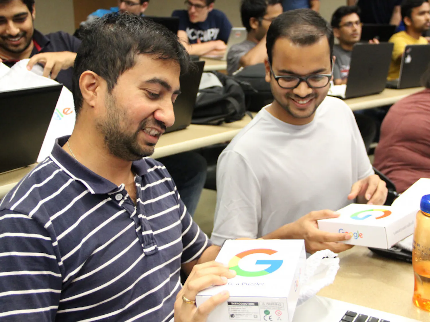 (From left to right) Master's computer science students, 35-year-old Pradeep Rajan and 25-year-old Harshit Vijayvargia, excitedly open goodie bags from Google. Rajan and Vijayvargia were some of the lucky few who ran up to get these bags.
