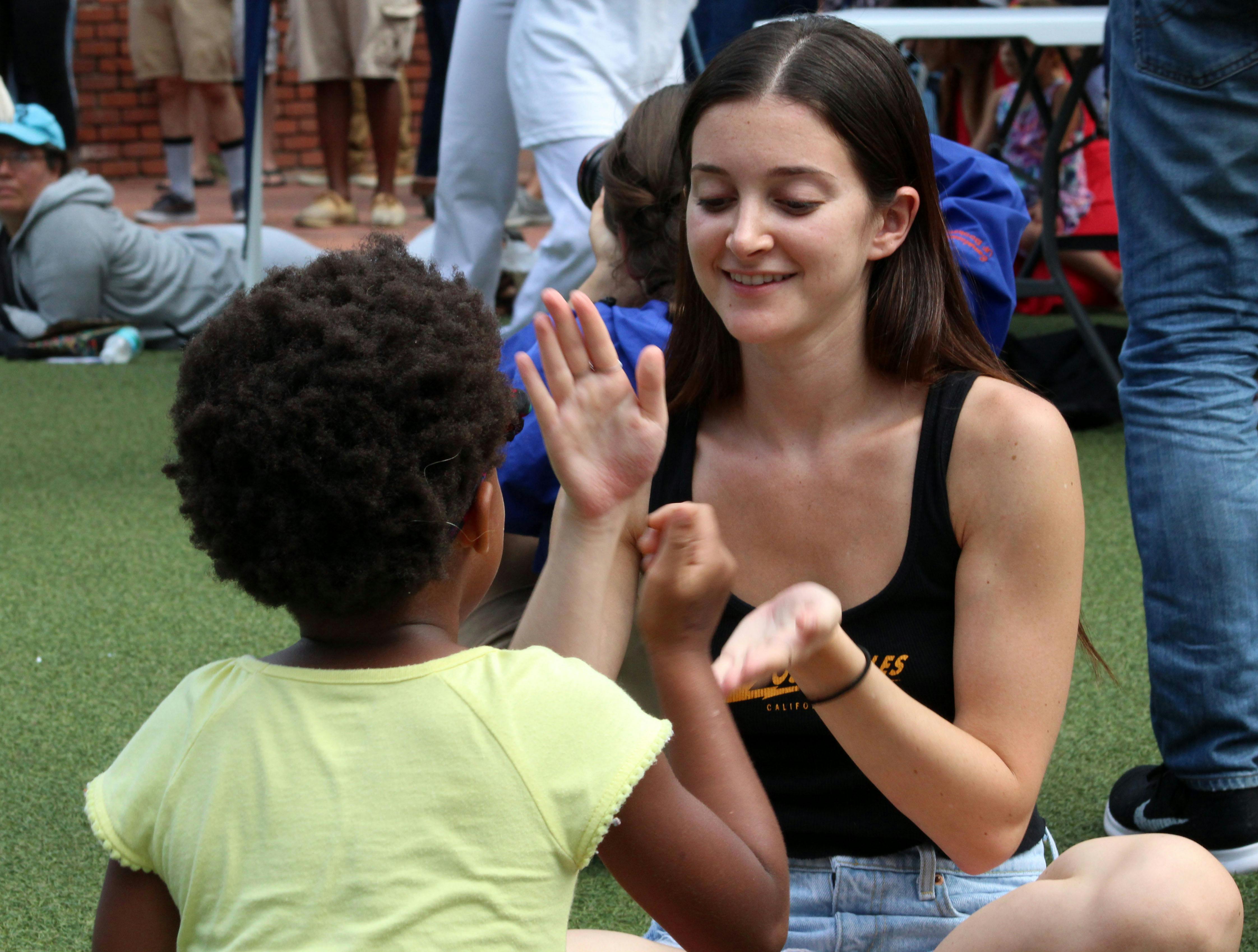 Calie Michael, a 21-year-old UF marketing and telecommunication senior, plays games with 7-year-old Nevaea on Saturday at the Downtown Latino Festival in Bo Diddley Plaza. “We just passed it on our way home and wanted to check it out,” Michael said. 