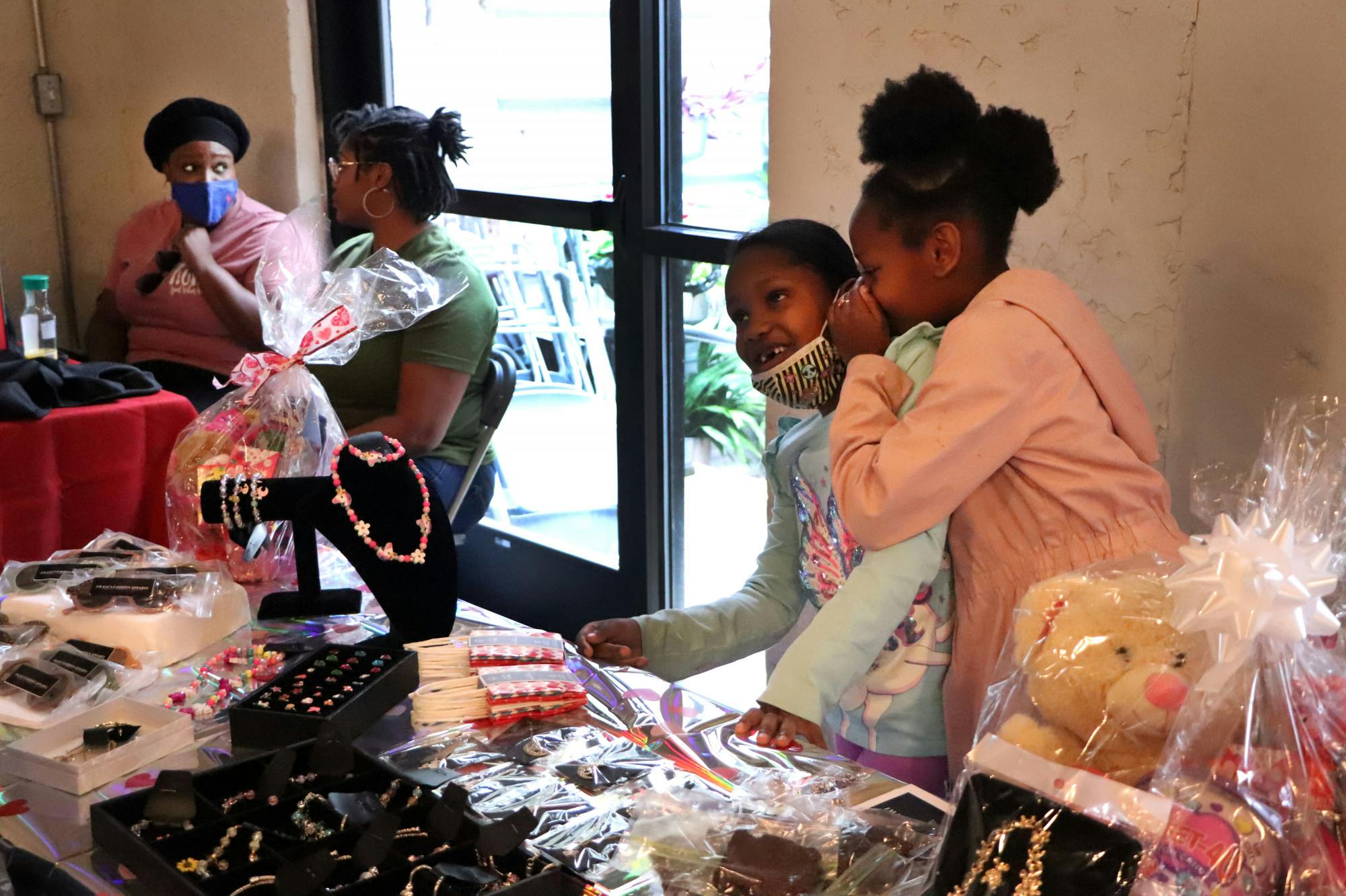 Londyn Merricks, 9, whispers in her cousin Imani Huggins', 7, ear at a Valentine's Day pop-up shop at Cypress & Grove Brewing Company on Saturday, Feb. 5. The pair was helping their mothers sell accessories.