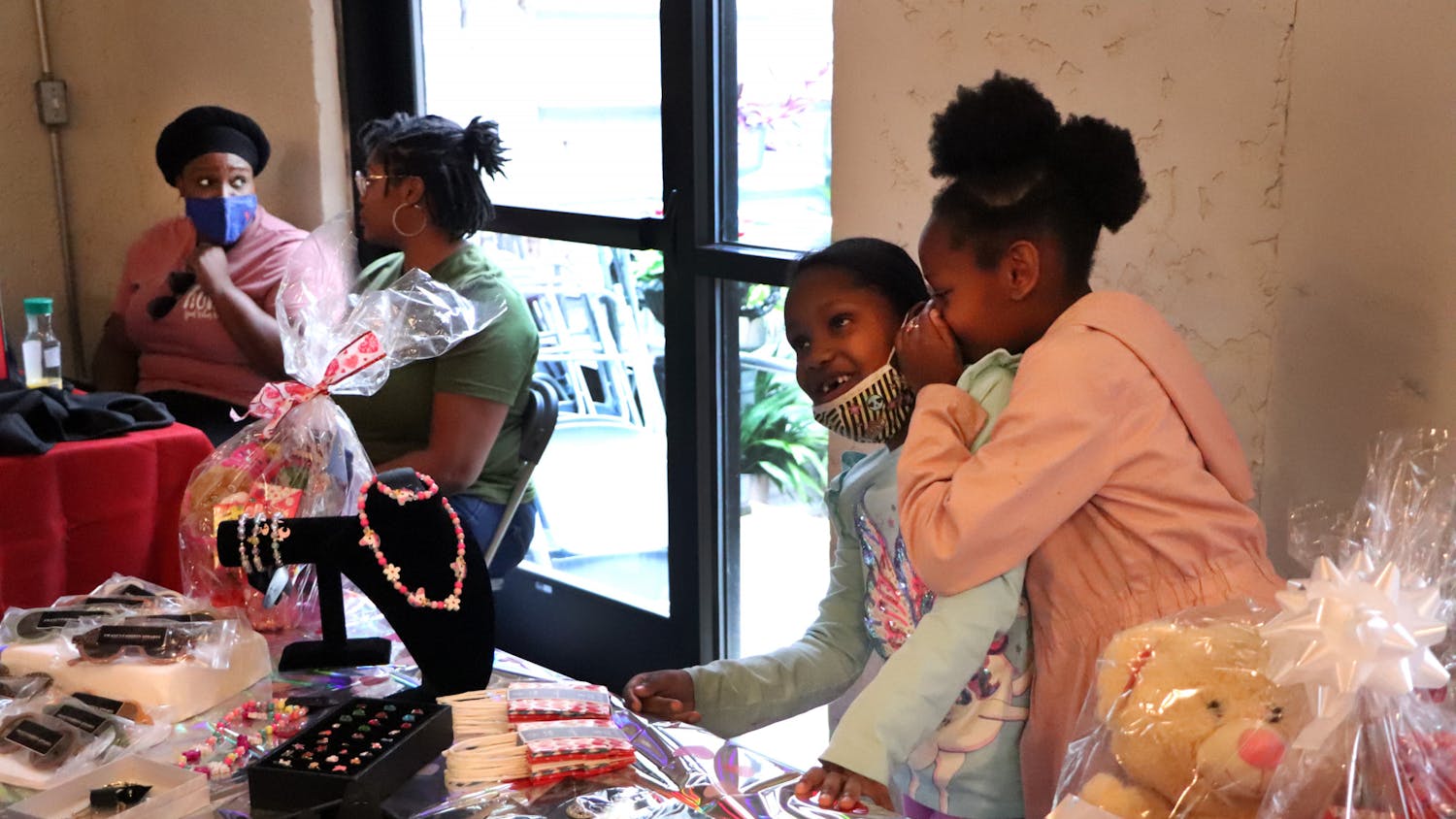 Londyn Merricks, 9, whispers in her cousin Imani Huggins', 7, ear at a Valentine's Day pop-up shop at Cypress & Grove Brewing Company on Saturday, Feb. 5. The pair was helping their mothers sell accessories.