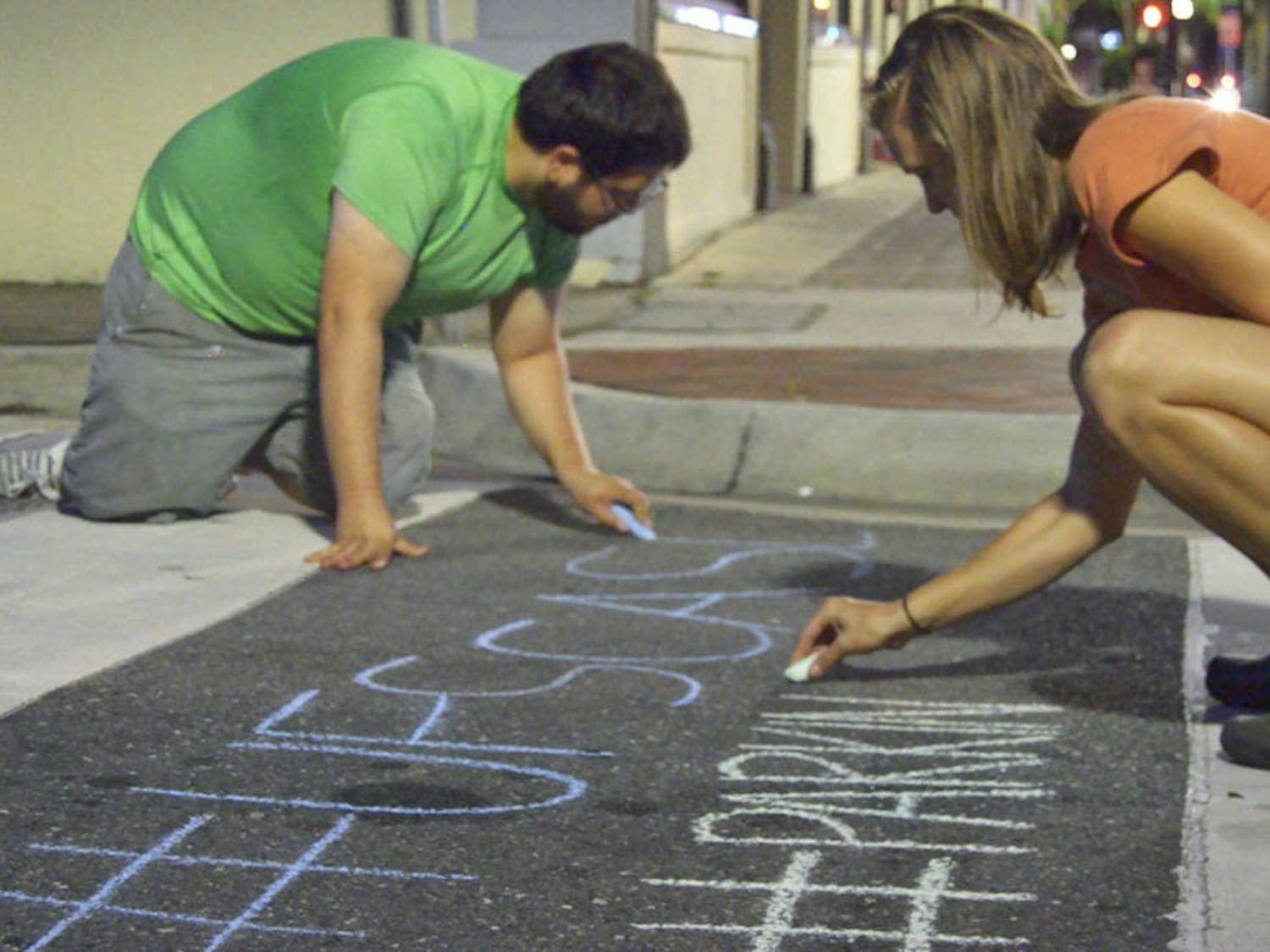 Daniel Rodriguez (left), a UF landscape architecture junior, and Lea Kindt, a UF landscape architecture freshman, both members of UF’s student chapter of America's Society of Landscape Architects chapter, write twitter hashtags on pavement downtown Saturday for the (PARK)ing Day event. The chapter coordinated with the Florida Community Design Center and Pop GNV to create "pop-up parks" on several corners of Northeast First Avenue on Friday and Saturday.