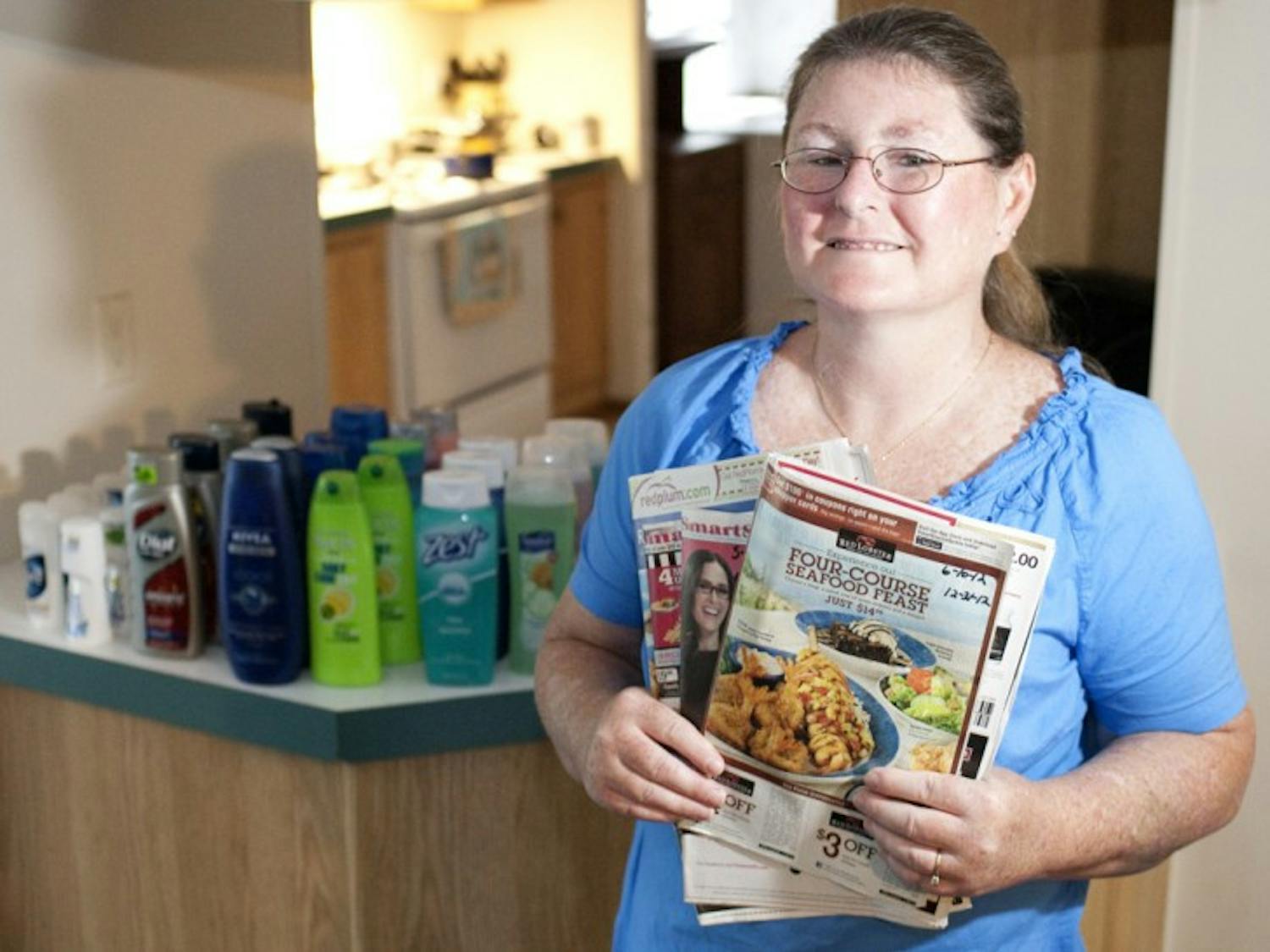 Angelia Gant, a 46-year-old security guard at the Atrium at Gainesville, poses at her home in front of her stockpile of goods collected through couponing.