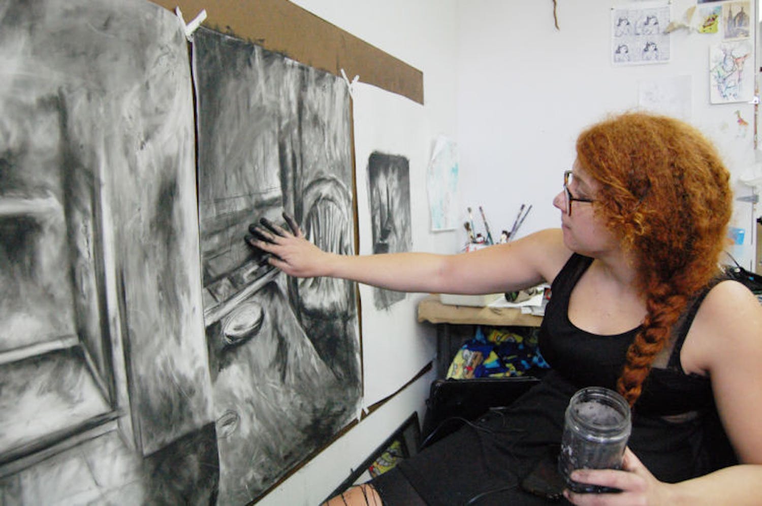 Dounia Bendris, a 21-year-old UF drawing senior, doesn’t like hard lines in her work, so she uses her fingers to smear her charcoal drawings. With black-stained hands, her fingerprints create a shadow and light effect. She dips her fingers into a water jug to seal the charcoal when she’s satisfied with an area.&nbsp;