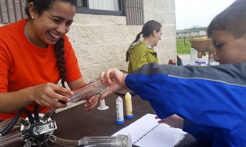 Animal science master student Carolina Collazos, 22, shows 6-year-old Wesley how an automatic cow milker works at the UF/IFAS Family Day at the Dairy. Collazos and other staff taught the public about milk production and the industry.