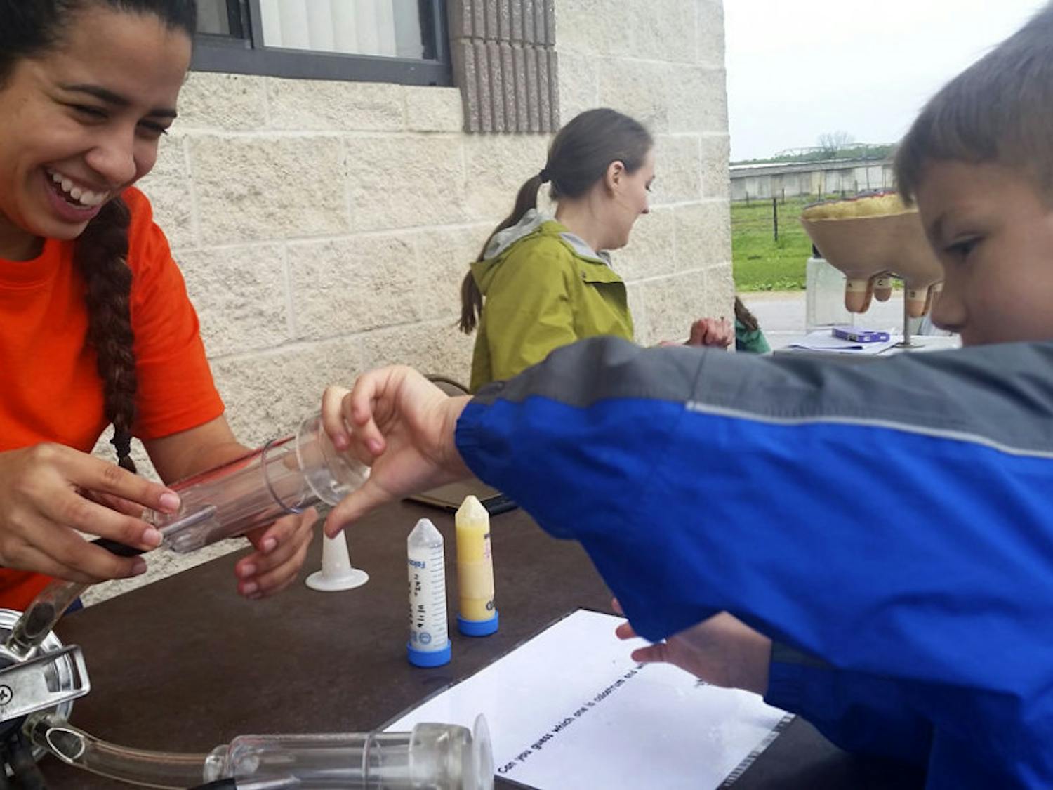 Animal science master student Carolina Collazos, 22, shows 6-year-old Wesley how an automatic cow milker works at the UF/IFAS Family Day at the Dairy. Collazos and other staff taught the public about milk production and the industry.