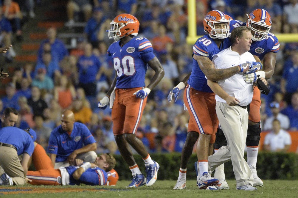 Florida coach Jim McElwain is restrained by tight end DeAndre Goolsby (30) and offensive lineman Fred Johnson (74) after McElwain showed his displeasure after quarterback Luke Del Rio, left, was knocked out of the game during the second half of an NCAA college football game against North Texas in Gainesville, Fla., Saturday, Sept. 17, 2016. North Texas was penalized for roughing the passer. (AP Photo/Phelan M. Ebenhack)