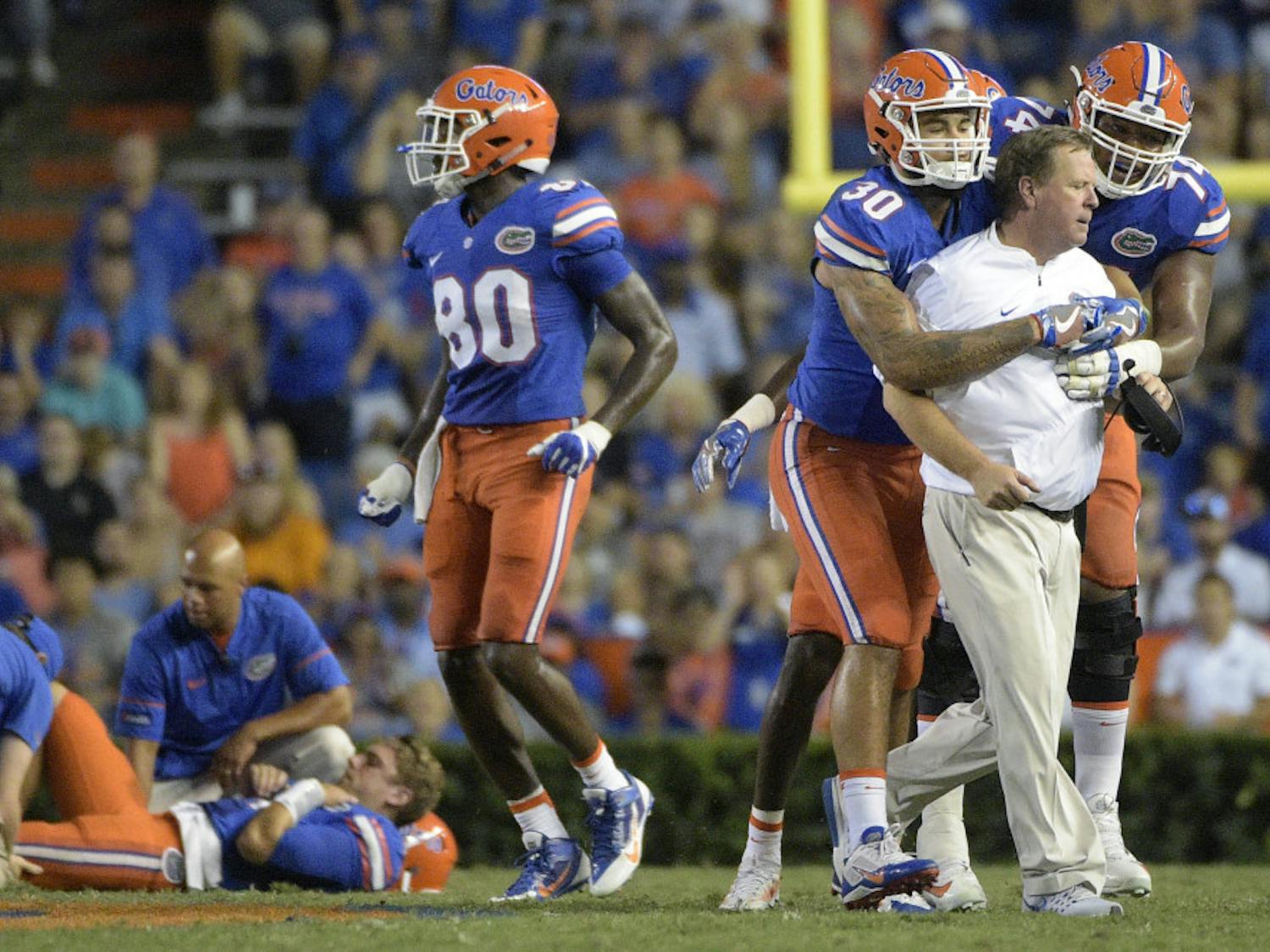 Florida coach Jim McElwain is restrained by tight end DeAndre Goolsby (30) and offensive lineman Fred Johnson (74) after McElwain showed his displeasure after quarterback Luke Del Rio, left, was knocked out of the game during the second half of an NCAA college football game against North Texas in Gainesville, Fla., Saturday, Sept. 17, 2016. North Texas was penalized for roughing the passer. (AP Photo/Phelan M. Ebenhack)