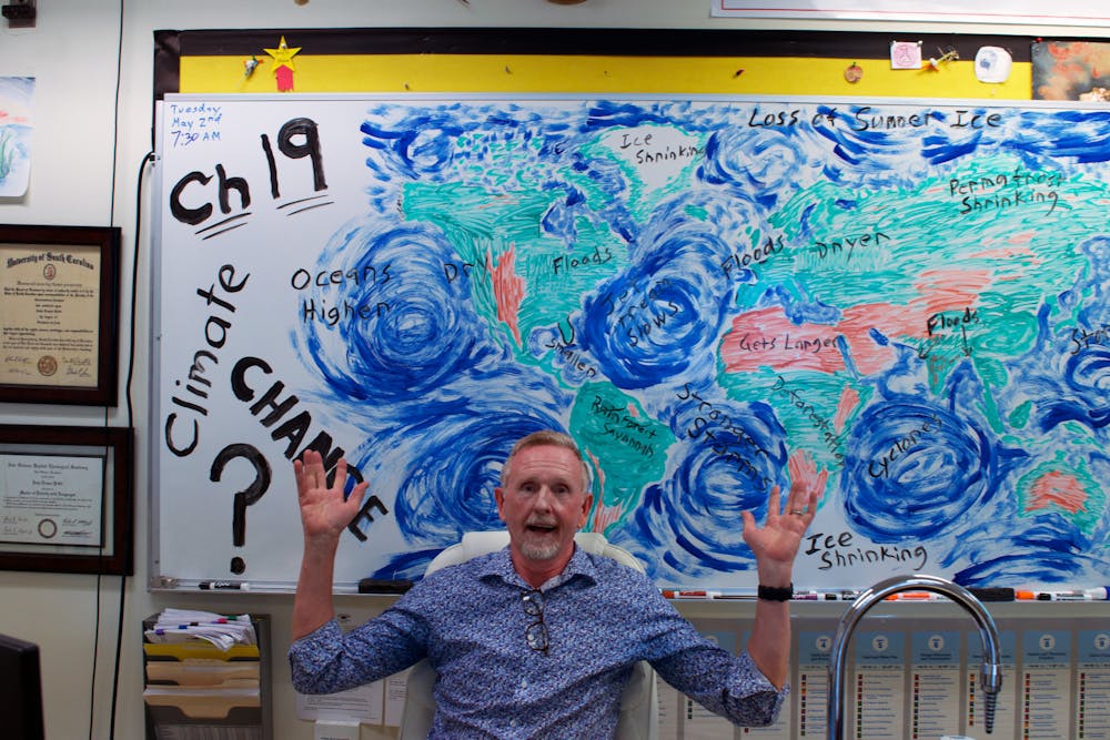 <p>AP Environmental Science Teacher John Pettit sits in front of his illustration of climate change he made earlier in the day as an example for his students at Buchholz High School Tuesday, April 4, 2023. </p>