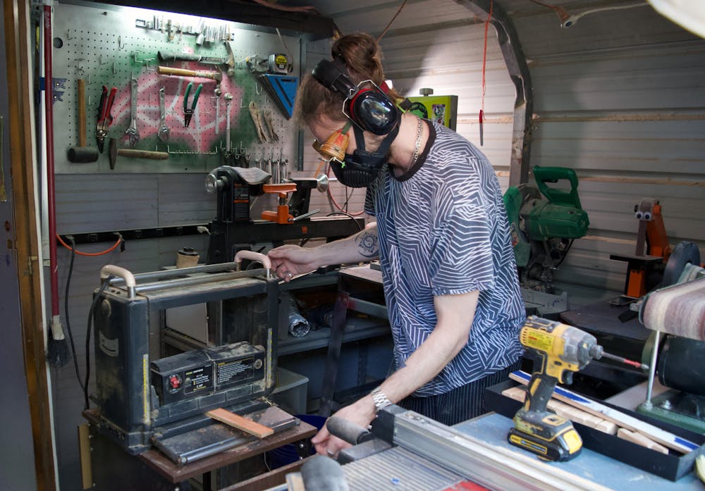 <p>Thomas Phillips removes the paint from pieces of broken skateboards that will be repurposed to make woodbots in his studio Friday, March 31, 2023.</p>