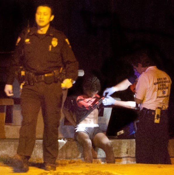 An alleged snatch-and-run robbery suspect is searched while sitting south of Phelps Laboratory after being apprehended by Alachua County Sheriffs Office Wednesday night.