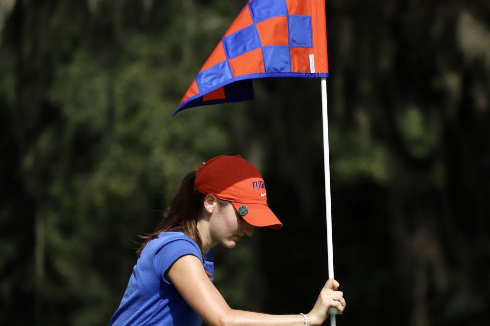 Freshman Maisie Filler adjusts a flag at Mark Bostick Golf Course. She sits in a tie for 21st after shooting three over par.