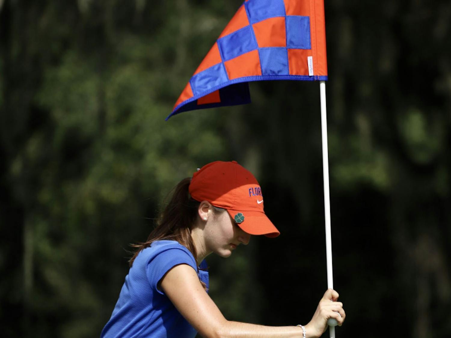 Freshman Maisie Filler adjusts a flag at Mark Bostick Golf Course. She sits in a tie for 21st after shooting three over par.