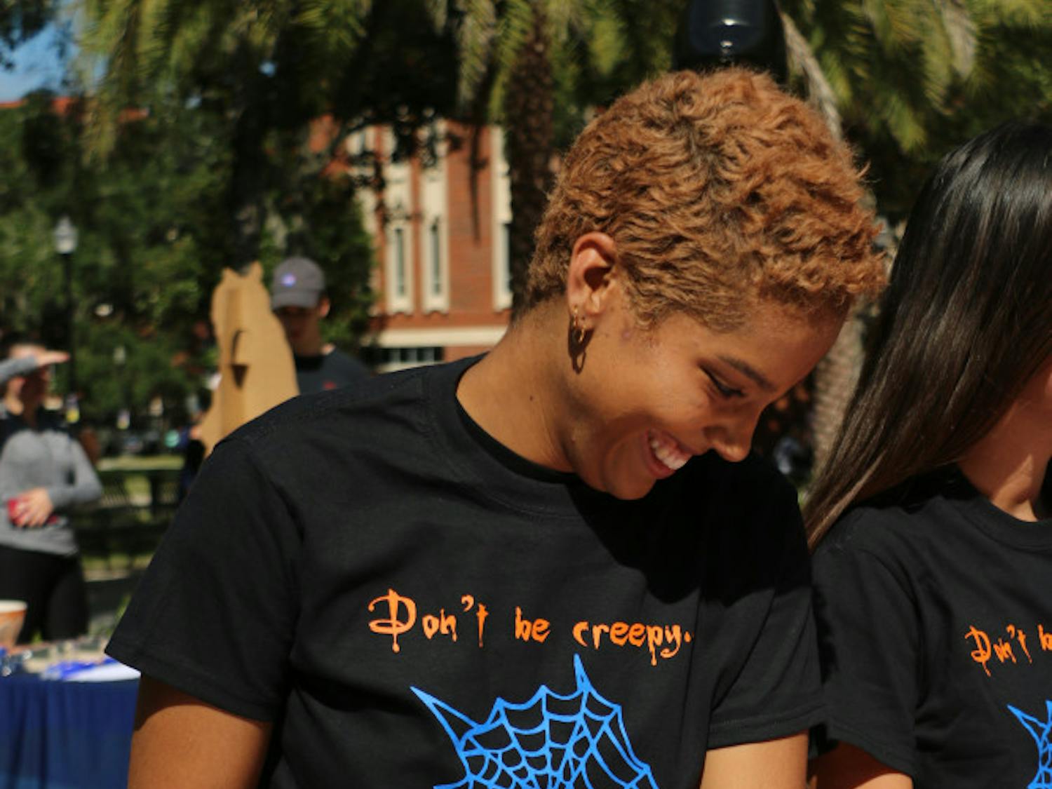 Alissa Adam, a 21-year-old UF women's studies and African-American studies senior, reads off some of the myths and facts of domestic violence during the My Costume is Not Consent tabling event at the Plaza of the Americas Wednesday afternoon. This event was hosted by the UFPD Office of Victim Services. Volunteers like Adam represented 11 other organizations that deal with domestic violence and its effects in the Gainesville area.