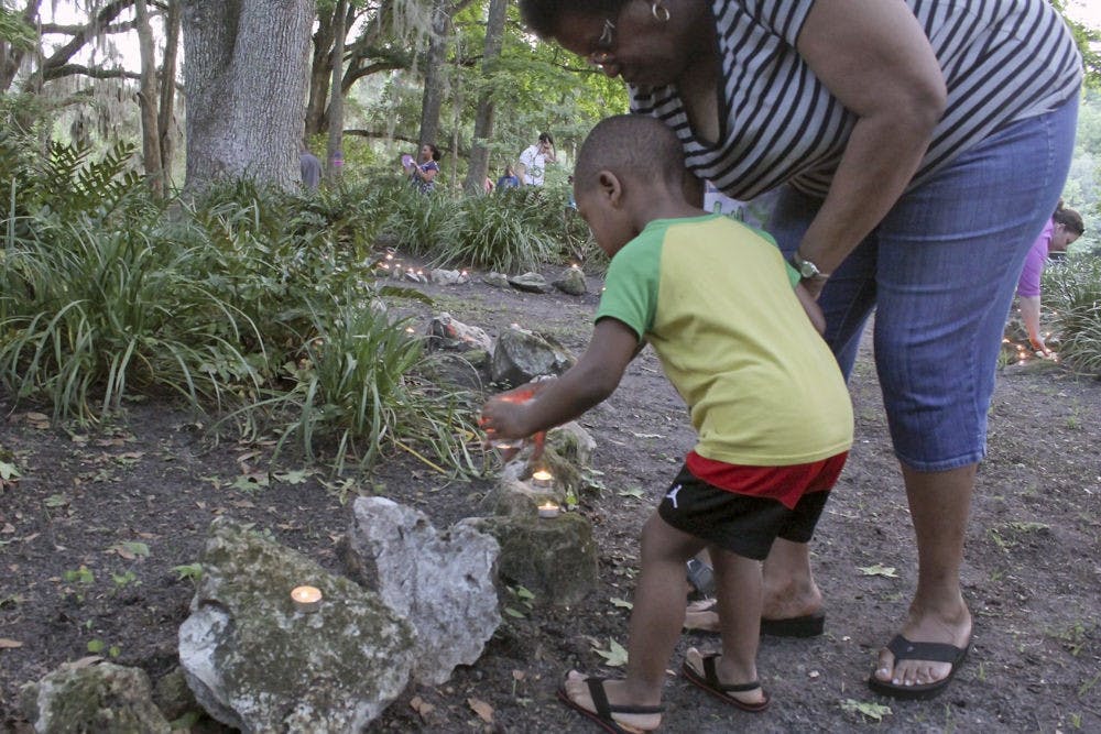 Mykeal Duggan, 3, and grandmother Alice Foreman, 61, place candles at the Victims' Memorial Park in Squirrel Ridge Park on Tuesday. This was the 25th candlelight vigil at the Victims' Memorial Park