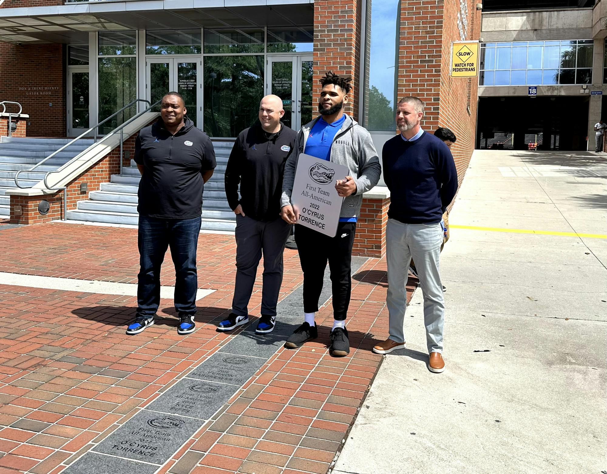 Former Gators offensive guard O'Cyrus Torrence receives his All-American brick alongside UF assistant coaches Darnell Stapleton and Rob Sale, and head coach Billy Napier on Wednesday, March 29, 2023. 