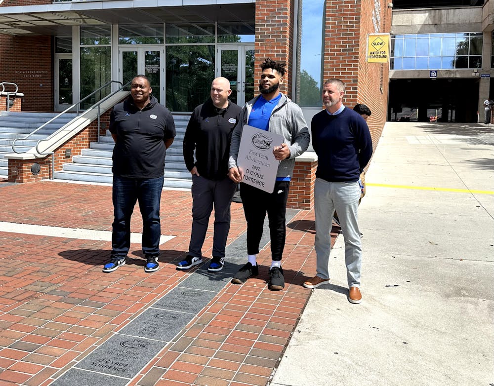 Former Gators offensive guard O'Cyrus Torrence receives his All-American brick alongside UF assistant coaches Darnell Stapleton and Rob Sale, and head coach Billy Napier on Wednesday, March 29, 2023. 