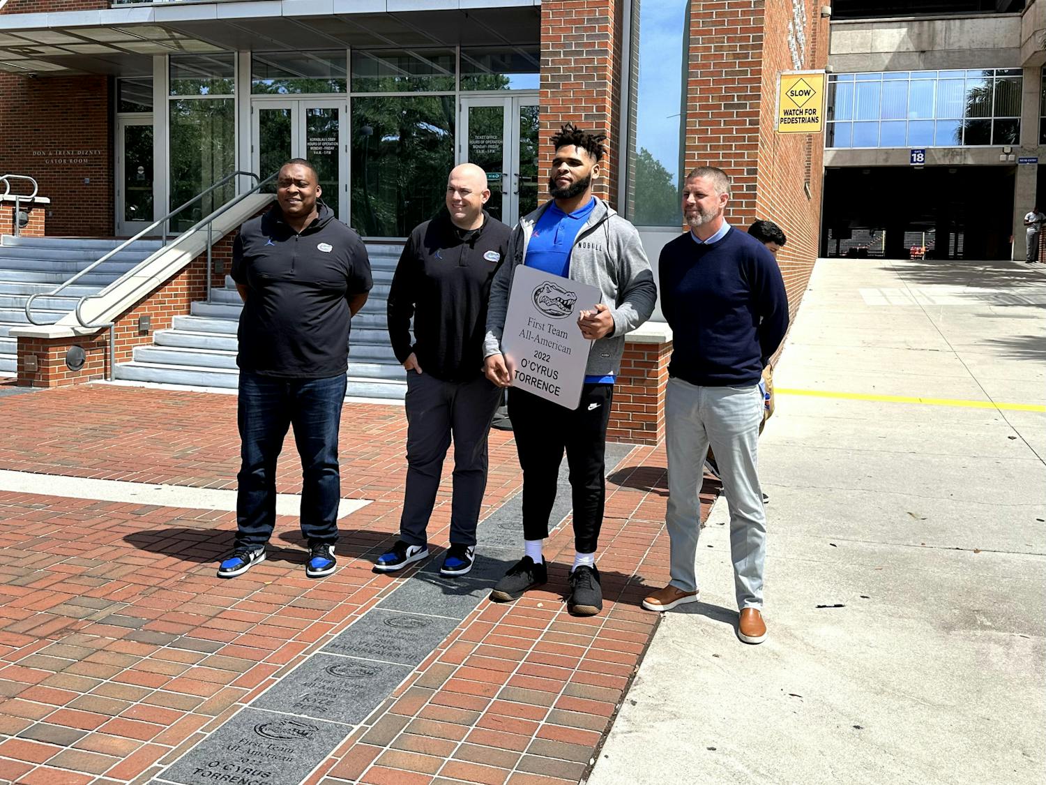 Former Gators offensive guard O'Cyrus Torrence receives his All-American brick alongside UF assistant coaches Darnell Stapleton and Rob Sale, and head coach Billy Napier on Wednesday, March 29, 2023. 
