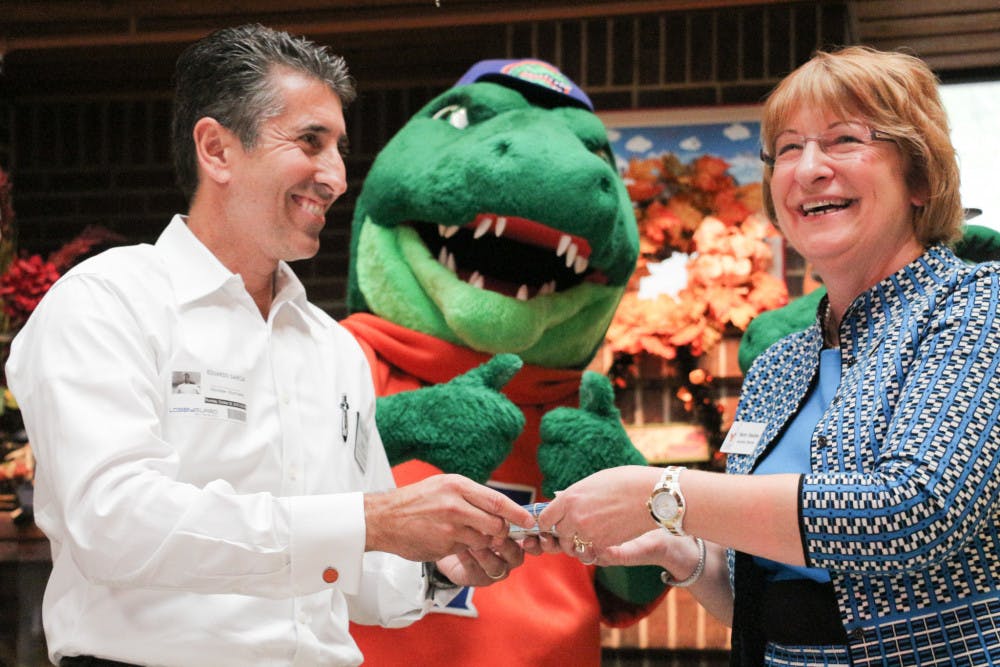 Eddie Garcia, a regional vice president of Winn-Dixie, hands Sherry Houston, the executive director of Ronald McDonald House Gainesville, 250 tickets to the last home game. 