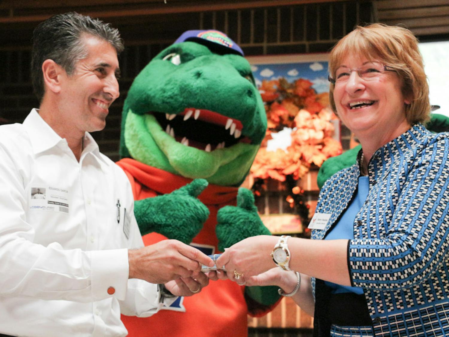Eddie Garcia, a regional vice president of Winn-Dixie, hands Sherry Houston, the executive director of Ronald McDonald House Gainesville, 250 tickets to the last home game.
