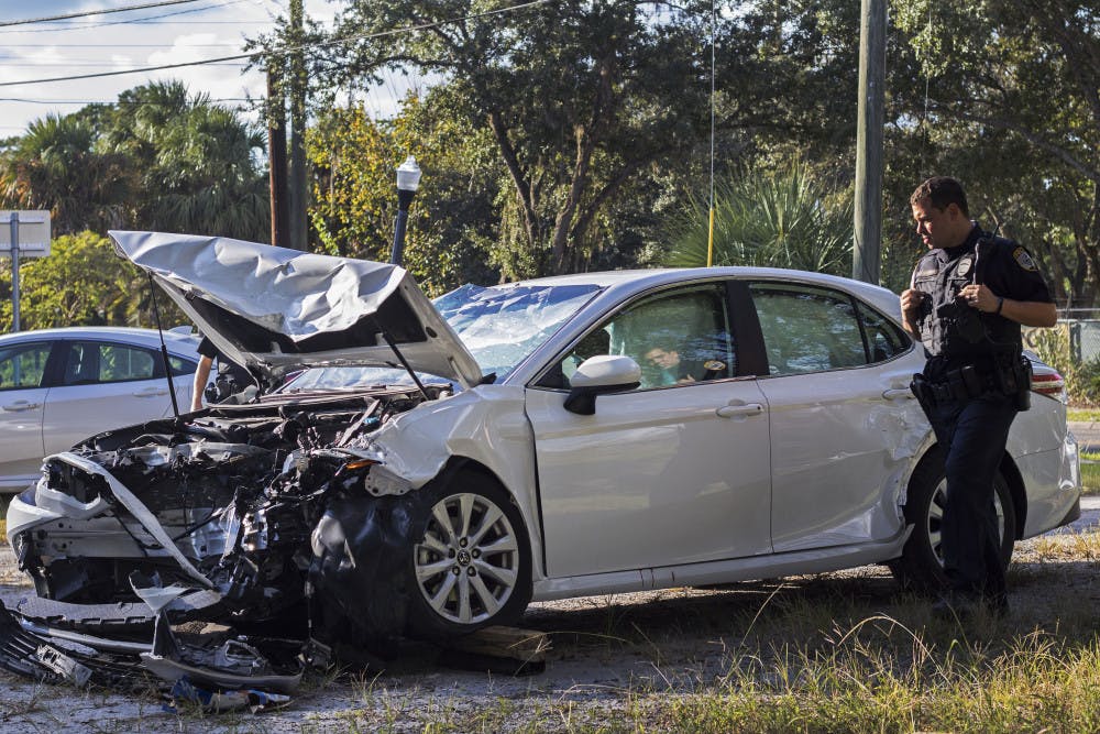Officer R. Schugan inspects a damaged vehicle Sunday afternoon following an accident near the intersection of Northeast Eighth Avenue and Waldo Road.  