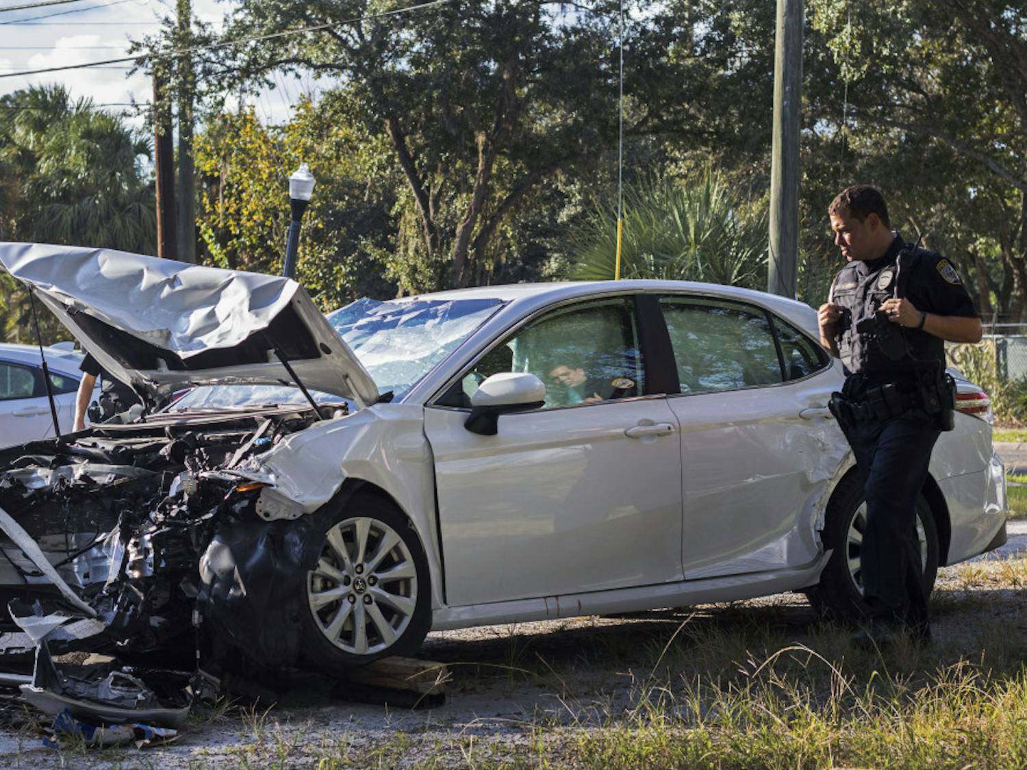 Officer R. Schugan inspects a damaged vehicle Sunday afternoon following an accident near the intersection of Northeast Eighth Avenue and Waldo Road.