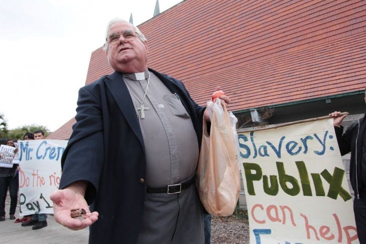 Father Les Singleton hold out pennies to supporters of fair wages for Immokalee workers. According to Singleton, it would only cost Publix a penny per tomato to pay the Immokalee workers fair wages.