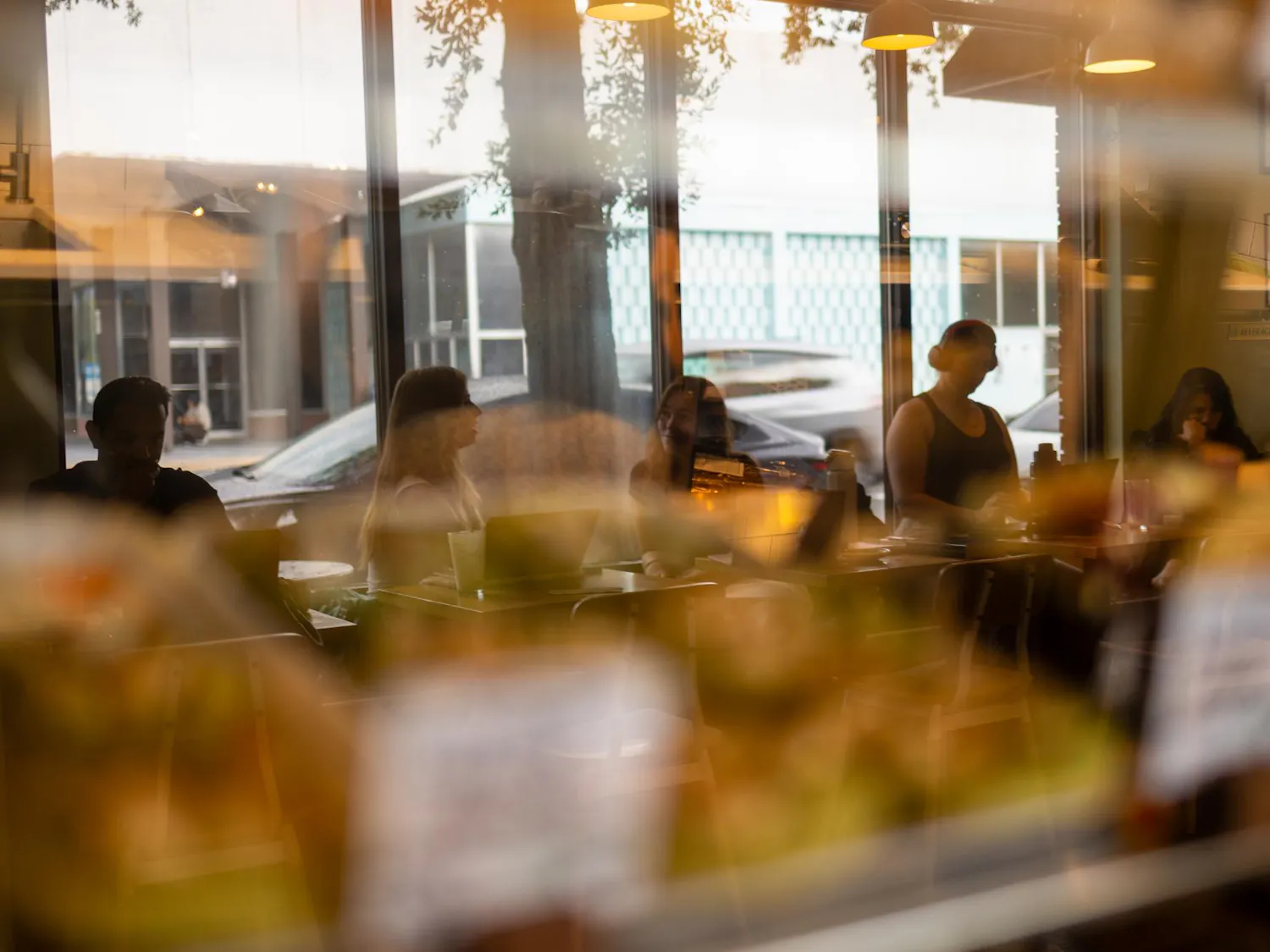 Customers of Karma Cream lounge in the cafe reflected in a pastry display case in Gainesville, Fla., Tuesday, Aug. 25, 2026.