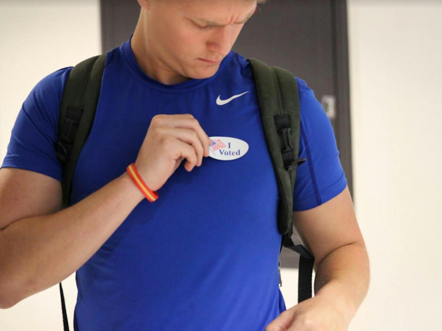 Nicholas Moore-Lefauve, a 20-year-old information systems and operations management major, puts on his "I Voted" sticker during the first day of early voting at the J. Wayne Reitz Union Monday morning. This is the third time Moore-Lefauve has voted in his life.