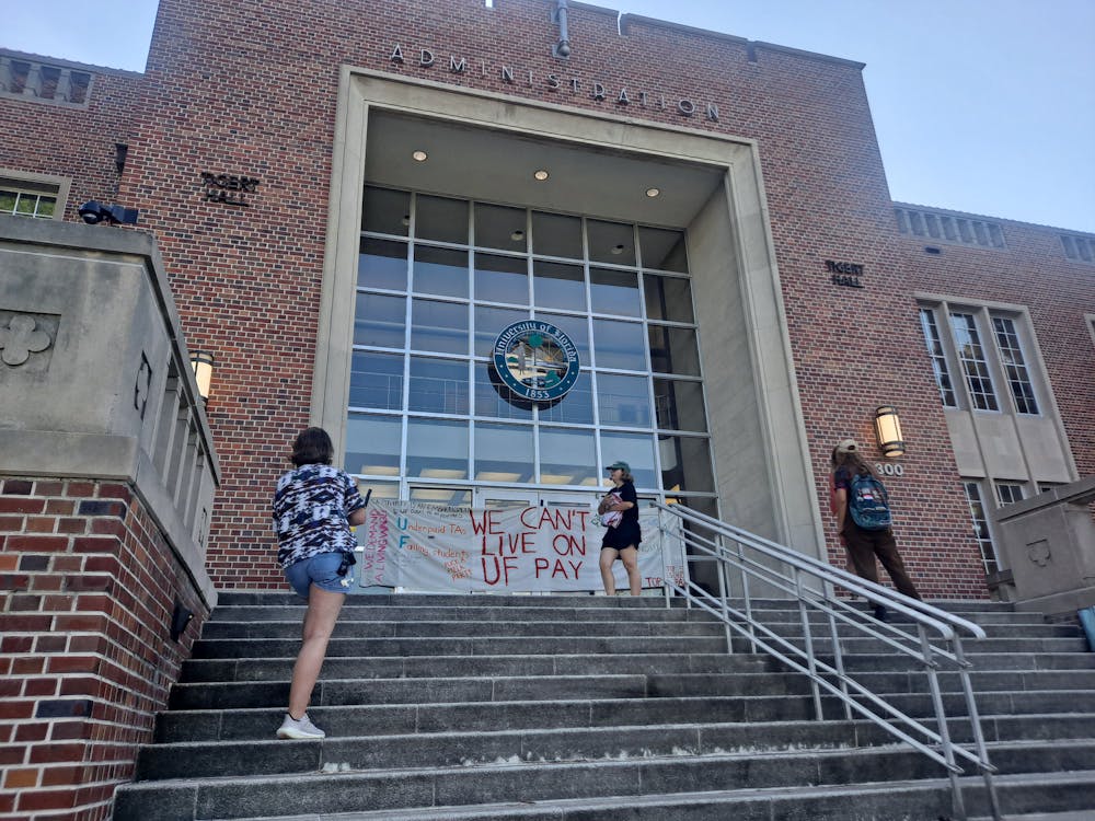 <p>Graduate students gather around a sign reading &quot;we can&#x27;t live on UF pay&quot; at Tigert Hall Friday, June 17, 2022. </p>