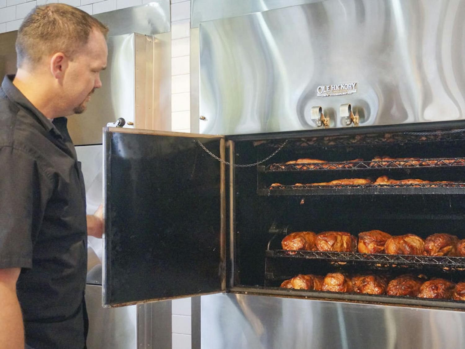 Coy Joyner, assistant general manager, opens one of the barbecue smokers at Sonny’s BBQ on 3635 SW Archer Road. The restaurant’s new building emphasizes the oak wood smokers, putting them in full view of guests.
