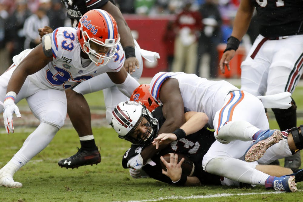 South Carolina's Ryan Hilinski, bottom, gets sacked by Florida's Zachary Carter, right, in the first half of an NCAA college football game Saturday, Oct. 19, 2019, in Columbia, SC. Florida defeated South Carolina 38-27.