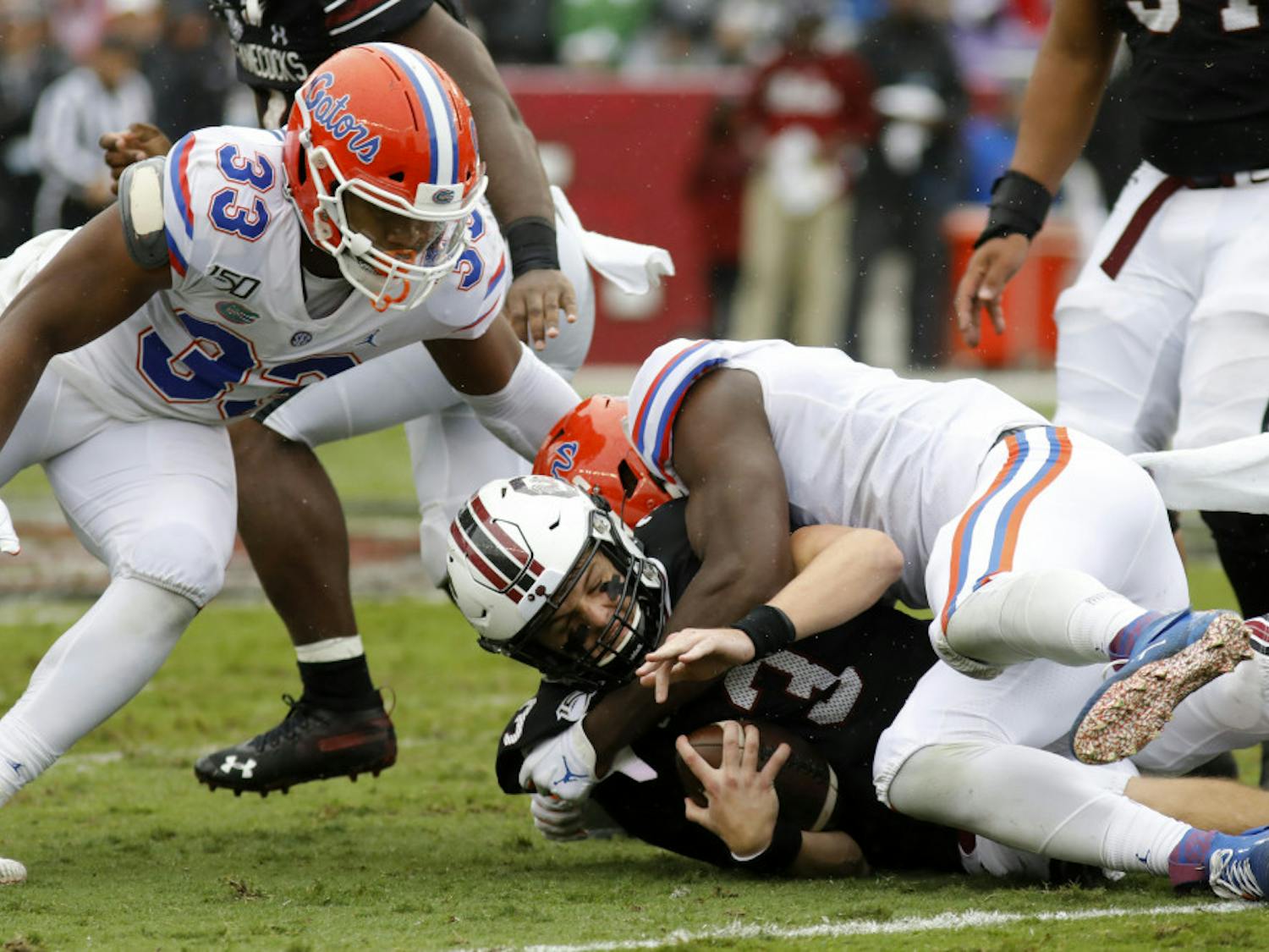 South Carolina's Ryan Hilinski, bottom, gets sacked by Florida's Zachary Carter, right, in the first half of an NCAA college football game Saturday, Oct. 19, 2019, in Columbia, SC. Florida defeated South Carolina 38-27.