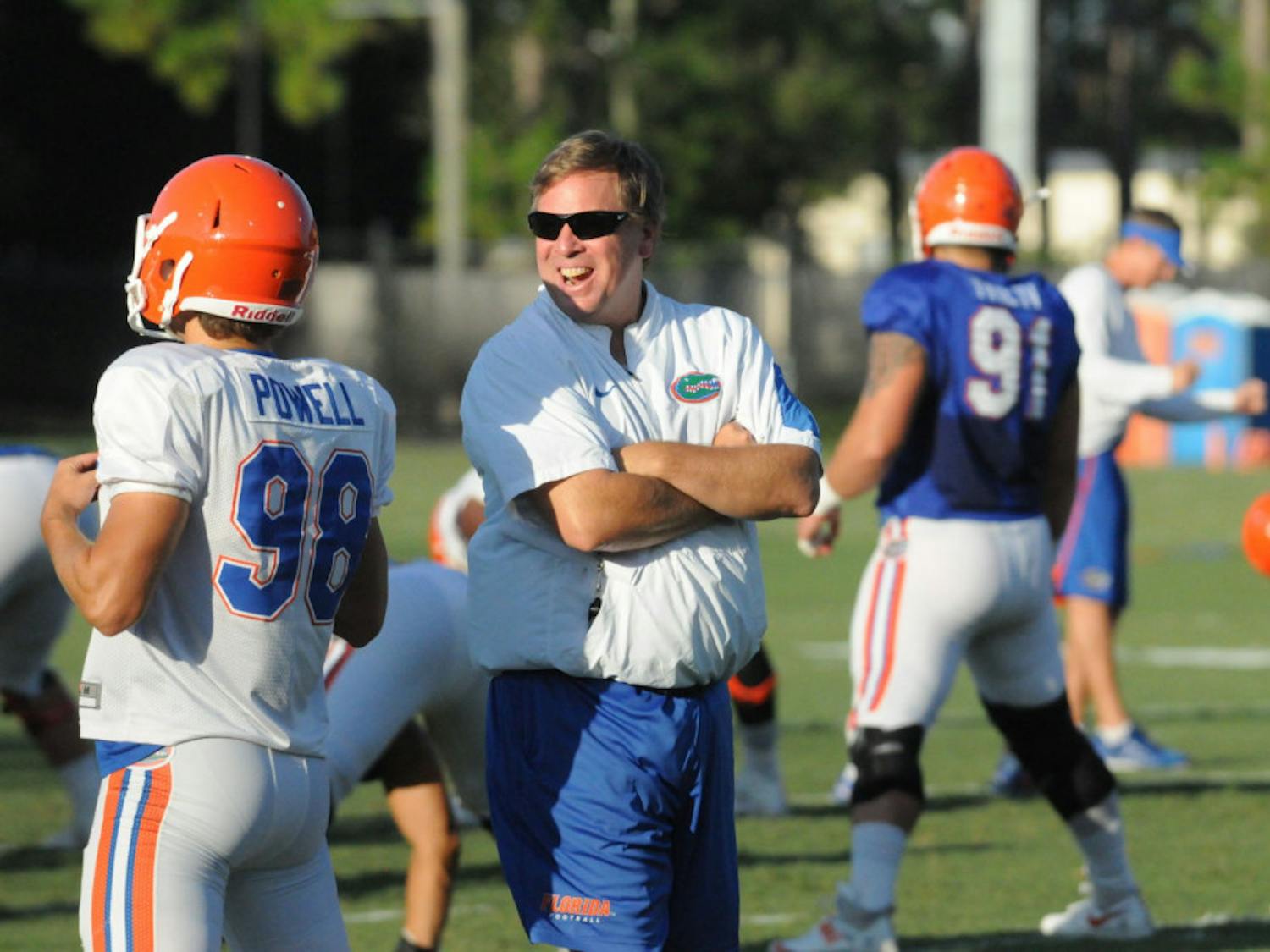 Jim McElwain talks with players during stretches before a fall practice at Donald R. Dizney Stadium. 