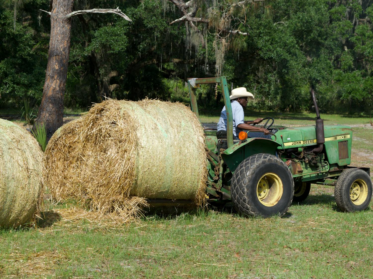 Farmer John Nix moves a bale of hay with a tractor near his cow pasture on Saturday, April 15, 2023.