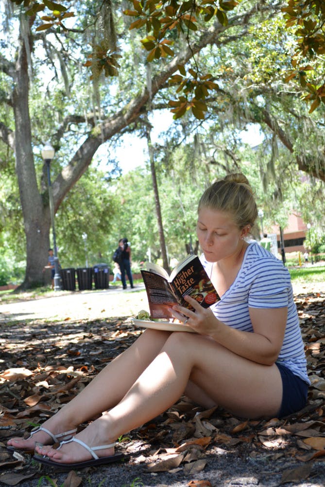 Kristin Chilton, a 21-year-old UF geology student, reads “The Higher Taste,” a Krishna cookbook, on the Plaza of the Americas Monday. 