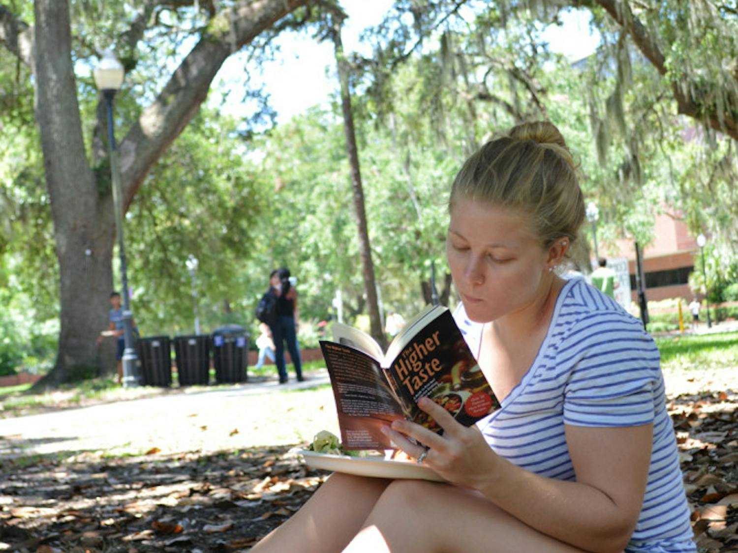 Kristin Chilton, a 21-year-old UF geology student, reads “The Higher Taste,” a Krishna cookbook, on the Plaza of the Americas Monday.