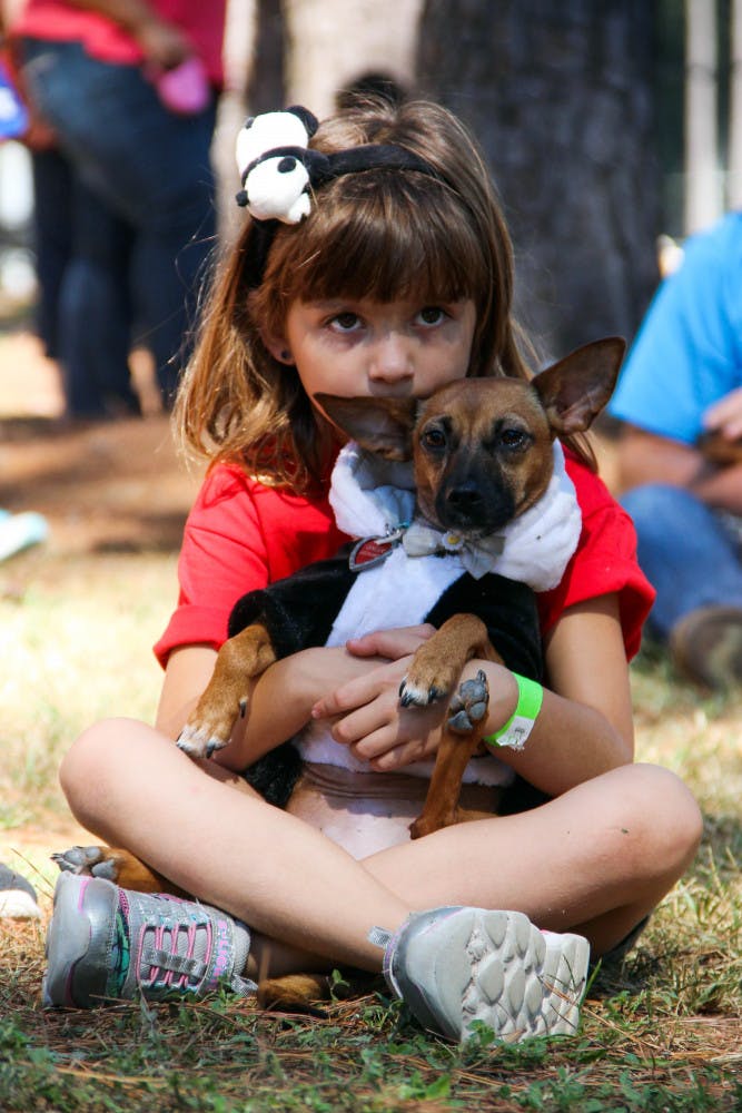 Seven-year-old Abigail Leonard holds her 3-year-old dog, Ginger, on Sunday during the annual Halloweener Derby. The Leonard family adopted Ginger after she was displaced by Hurricane Irma.