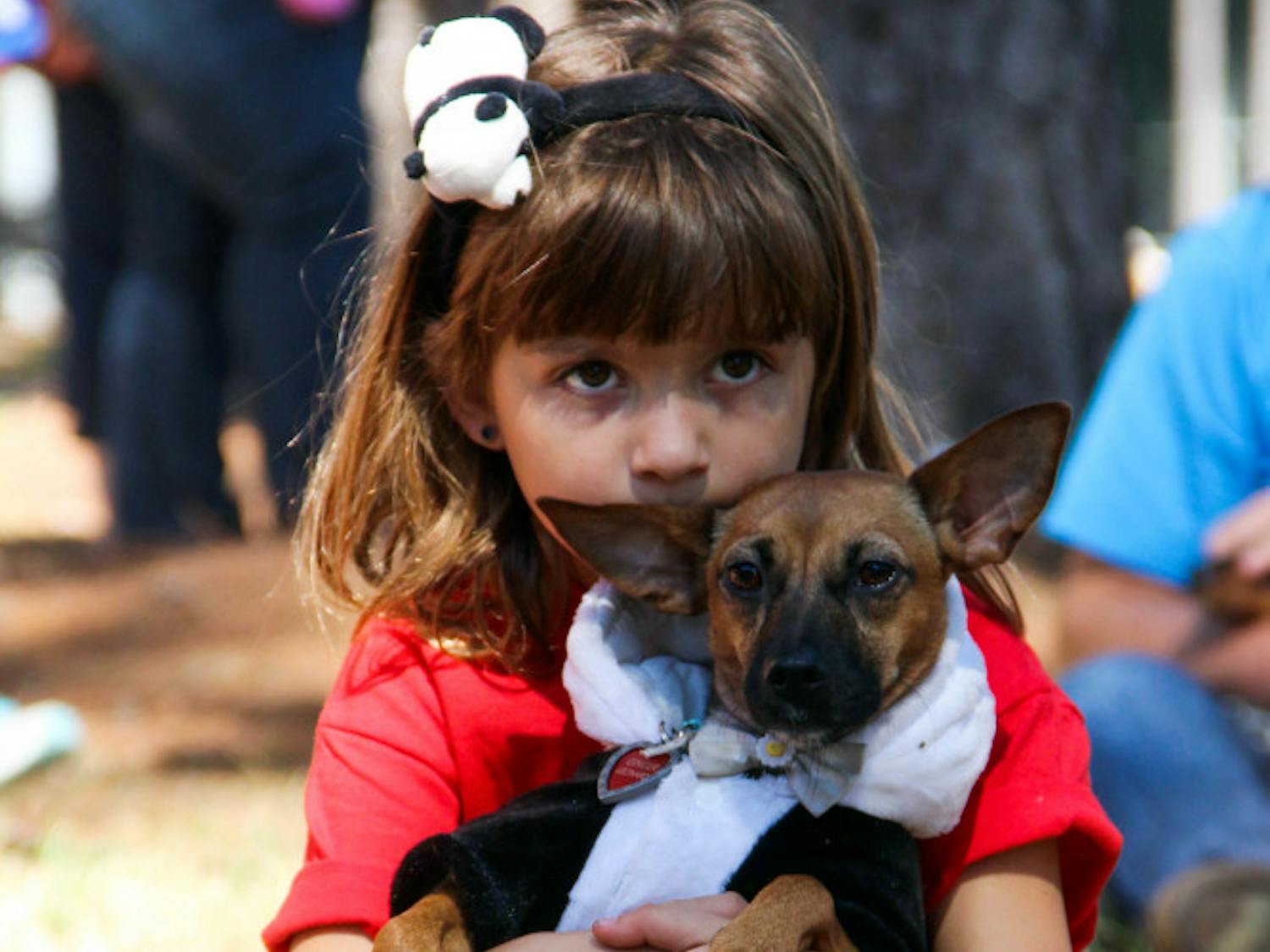 Seven-year-old Abigail Leonard holds her 3-year-old dog, Ginger, on Sunday during the annual Halloweener Derby. The Leonard family adopted Ginger after she was displaced by Hurricane Irma.