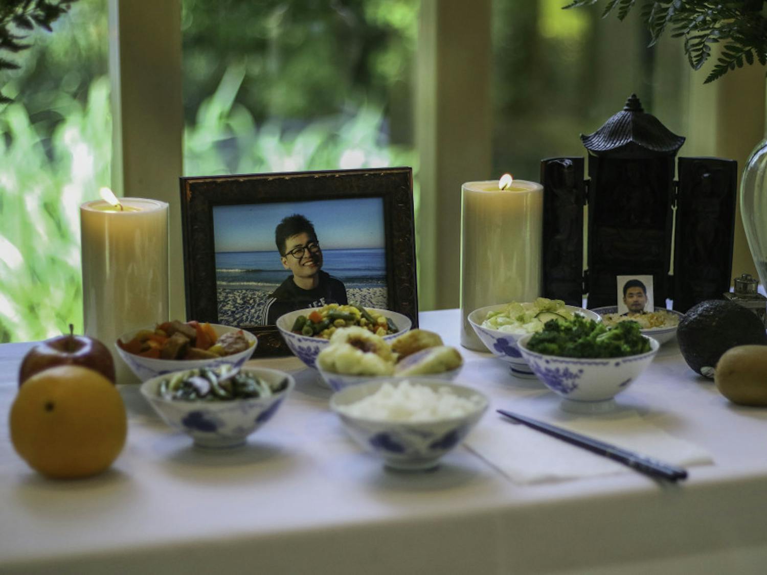 A memorial for Huixiang Chen, a University of Florida international doctoral candidate who died by suicide June 13, was made up of photos of Chen, candles and a variety of dishes Wednesday at the front of the Baughman Center during a celebration of life service. There was standing room only in the chapel as over 150 people gathered to remember Chen and pay respects to the family.