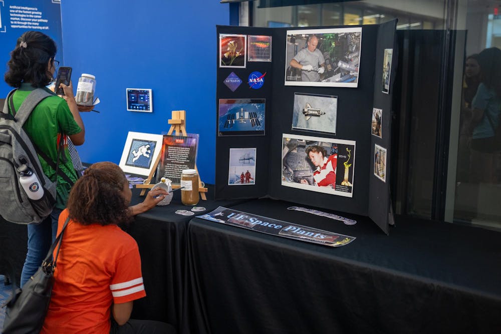 <p>Observers look at a UF space plants presentation at the Blue Origin New Shepard mission launch party at  the J. Wayne Reitz Student Union on Aug. 29, 2024. </p>