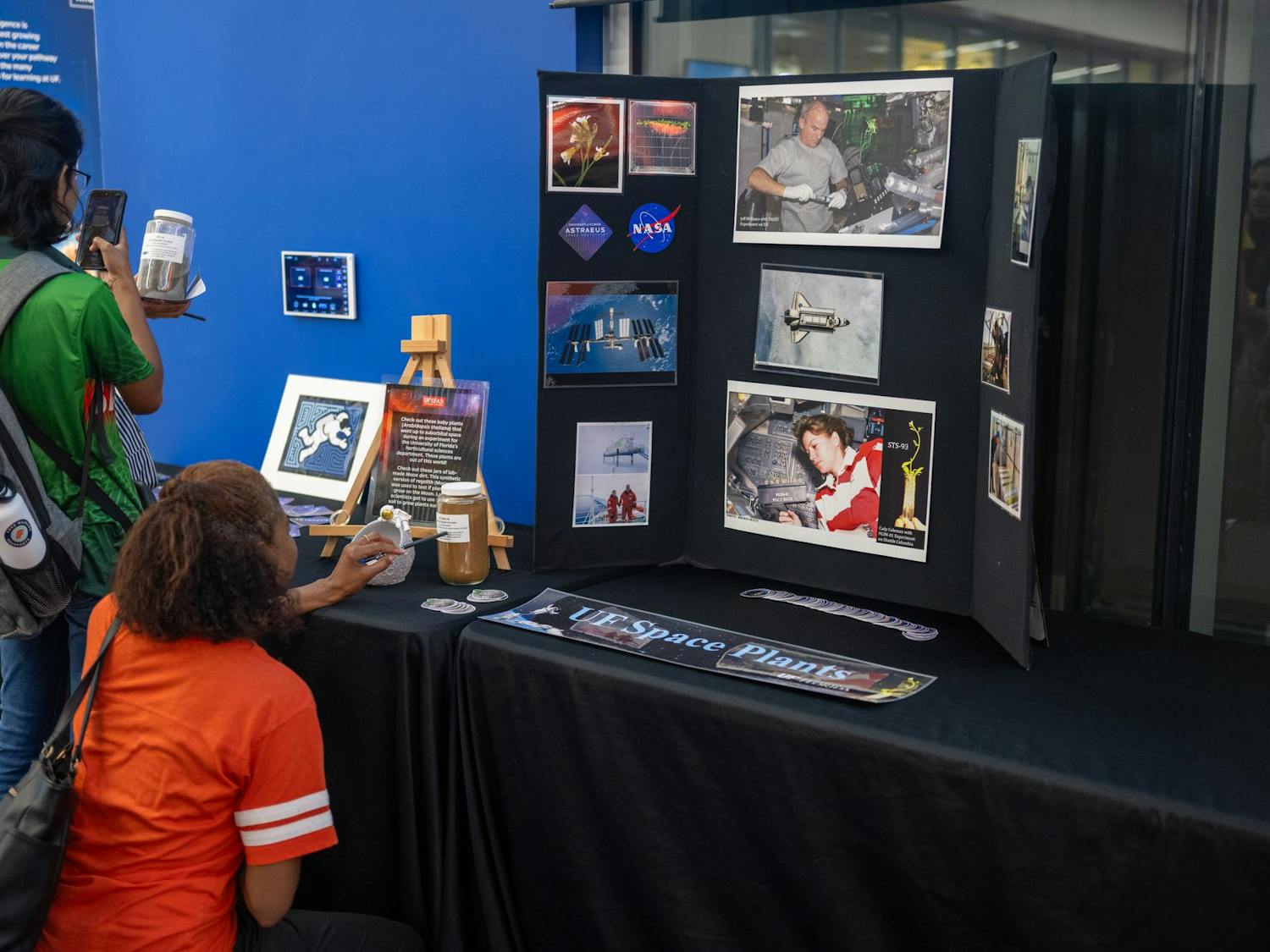 Observers look at a UF space plants presentation at the Blue Origin New Shepard mission launch party at the J. Wayne Reitz Student Union on Aug. 29, 2024.