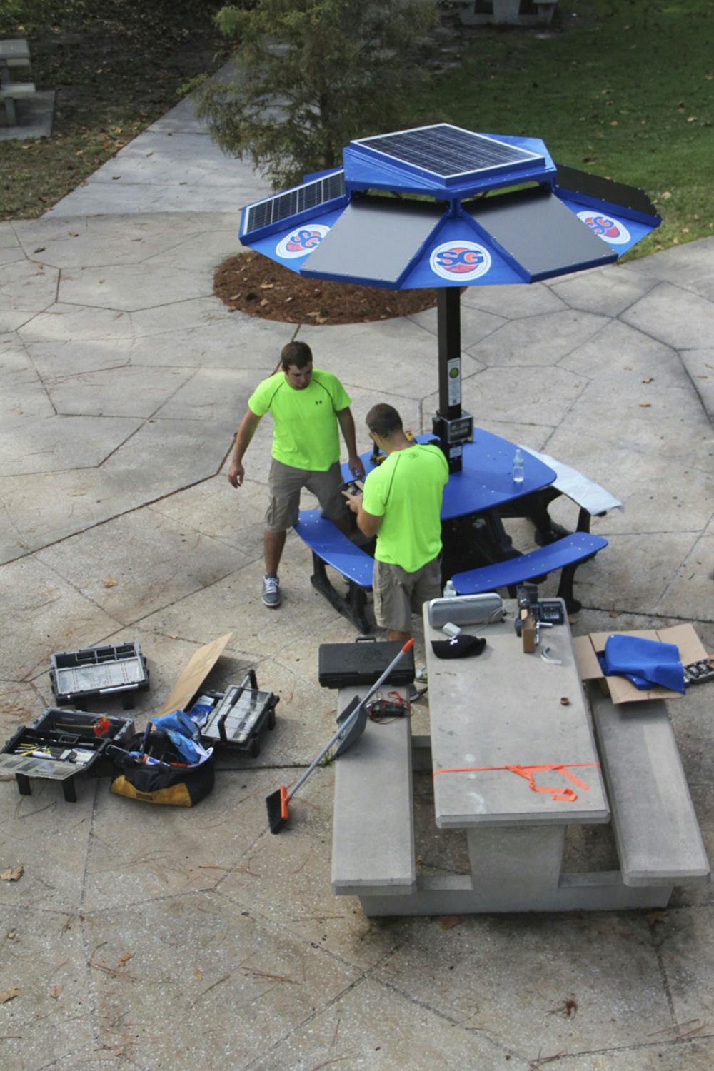 Bill McGinn, assistant director of UF Business Affairs and Joe and Joey Kobus of EnerFusion install a new solar-powered workstation outside the Hub on Tuesday. The station was funded by the UF Student Government. A similar work space can be found at Rawlings Plaza.