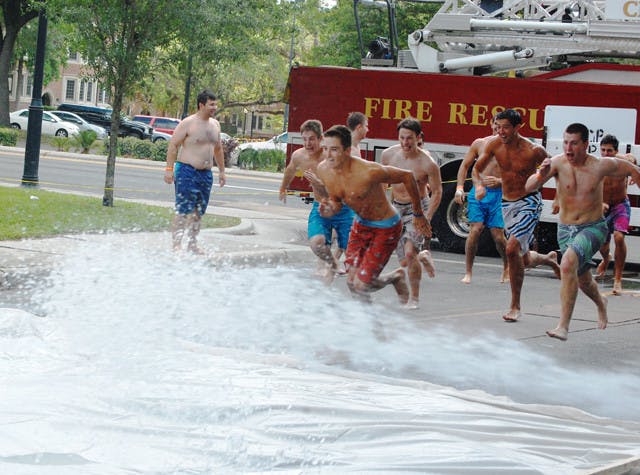 Participants run to slide down Pi Kappa Alpha's Tide Slide, a 100-foot long slip 'n slide being hosed down by the Gainesville Fire Department, that closed down 19th Street on Saturday. Admission was $5 for unlimited slides and all proceeds were donated to the Boys and Girls Club of Gainesville.