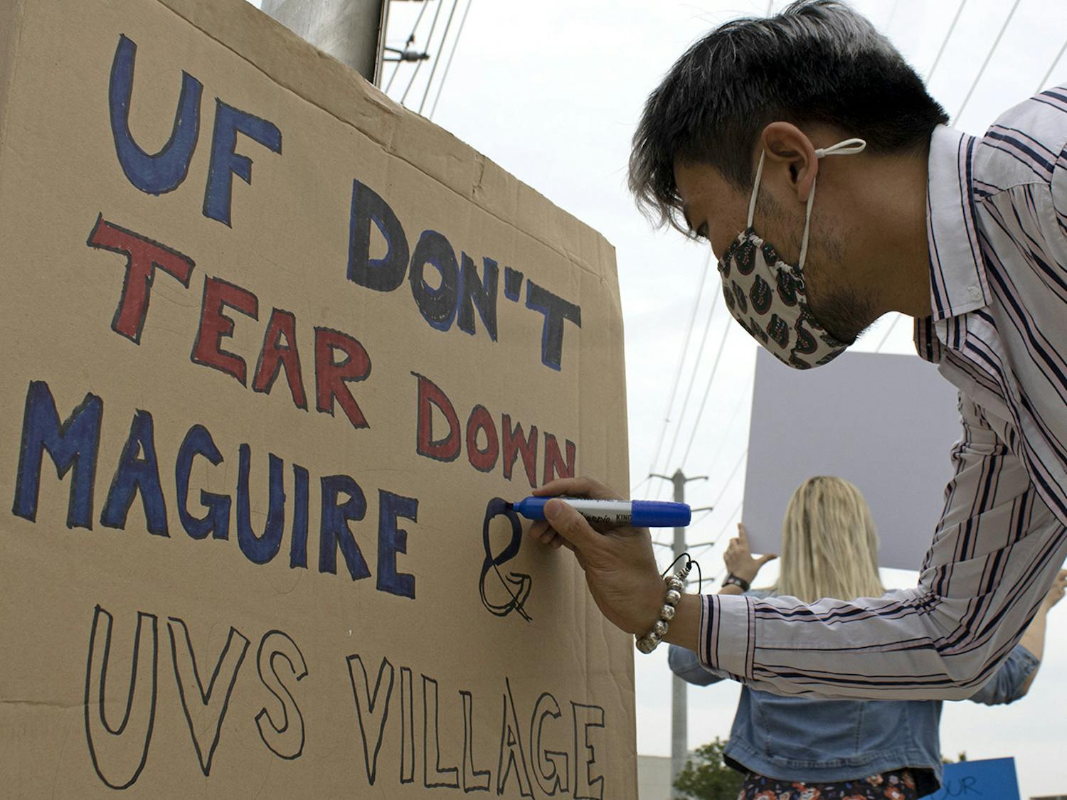 Edward Ke Sun, 30, a PhD candidate for architectural history, theory and criticism at UF, colors a sign that reads “UF Don’t Tear Down Maguire & UVS Village” on Friday, April 9, 2021. Sun protesting to raise awareness about UF’s plan to demolish three out of the five graduate student housing complexes in Gainesville.