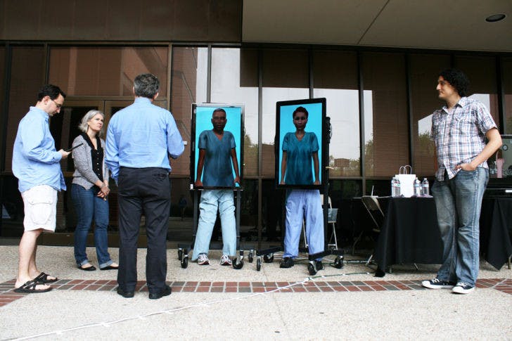 Andrew Robb, a 26-year-old UF Ph.D. student, far left, demonstrates to residents a computer project with “virtual humans,” designed to train people for interpersonal situations at the CISE Building on Monday.