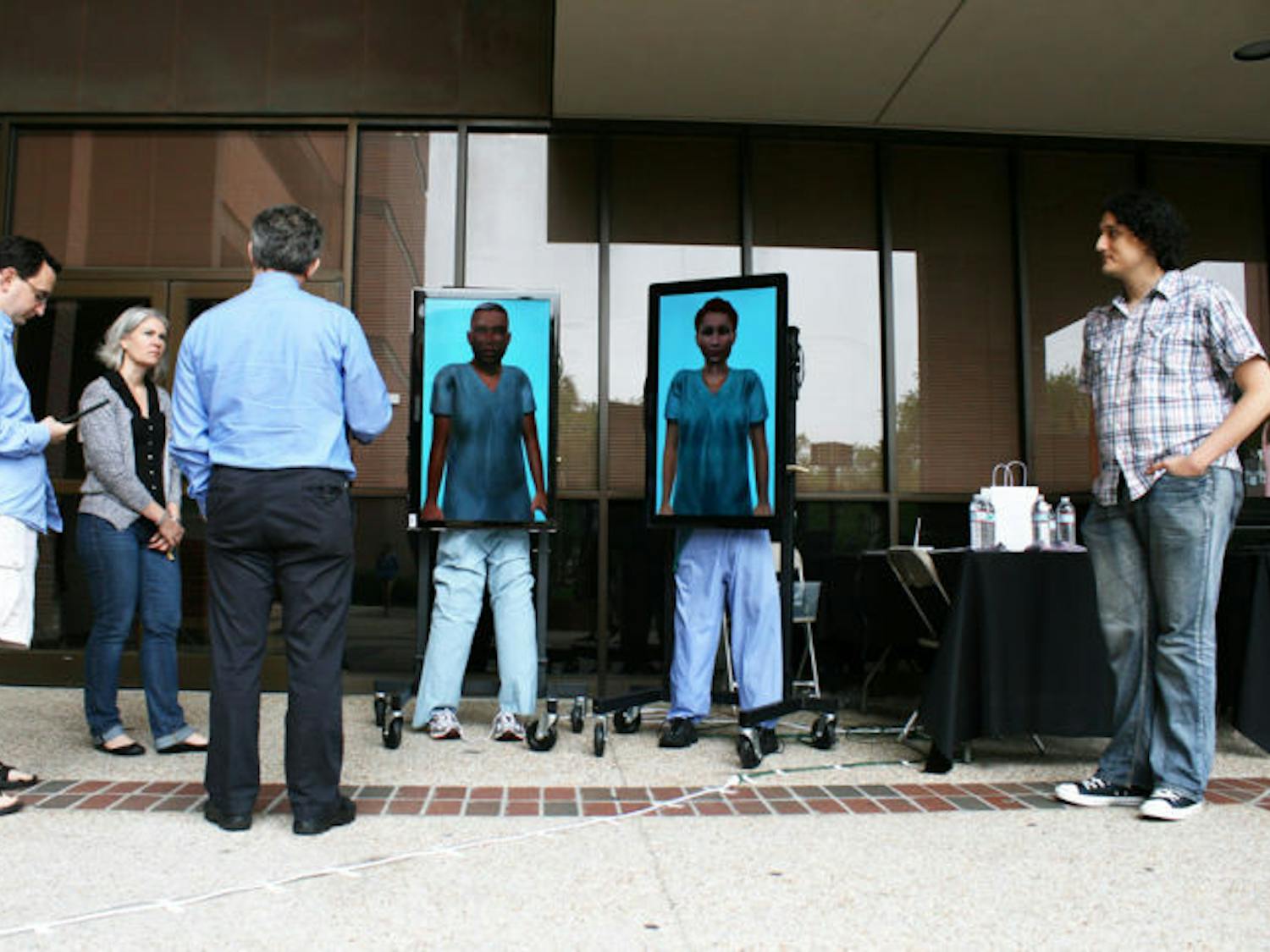 Andrew Robb, a 26-year-old UF Ph.D. student, far left, demonstrates to residents a computer project with “virtual humans,” designed to train people for interpersonal situations at the CISE Building on Monday.