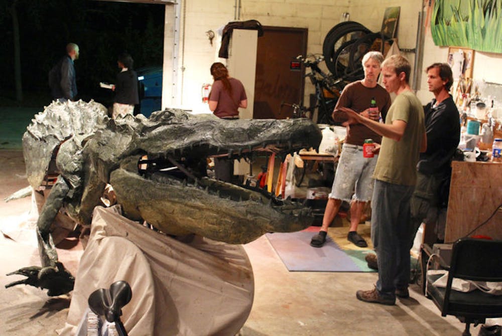 <p>John Patterson, left, Raymond Rawls, center, and Kevin Ratkus, right, wait for paint to dry Tuesday night after painting a 20-foot bicycle-powered parade float that will be a part of UF’s Homecoming Parade.</p>