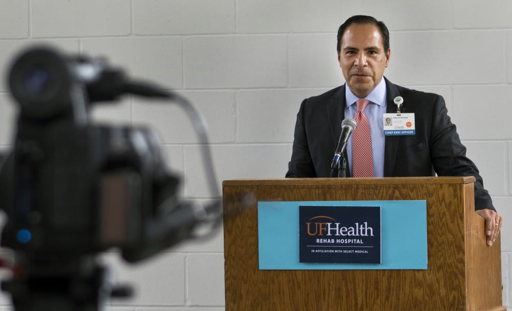 Edward Jimenez, the UF Health Shands chief executive officer, speaks Tuesday to an audience of about 50 people during a ribbon-cutting celebrating the upcoming opening of the UF Health Rehab Hospital. Jimenez was one of three speakers who made brief opening remarks before a rain shower cut the outdoor ceremony short. The new rehabilitation facility is located on 2708 SW Archer Road and is expected to begin admitting patients on Feb. 19.