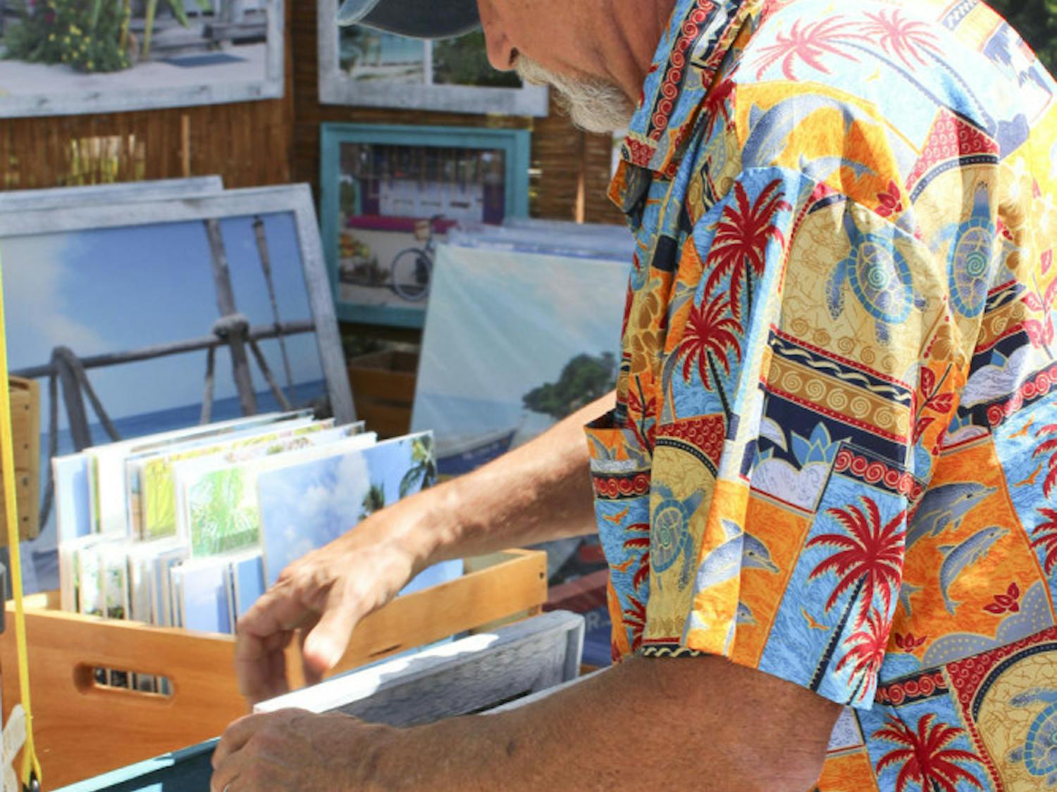 Ft. Pierce, Florida-based photographer Bill Dirienzo thumbs through picture frames on Sunday at the Santa Fe Spring Arts Festival in downtown Gainesville. Dirienzo has shot island photography for 10 years.